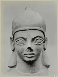 Limestone Neo-Cypriote head, front view, with a tall rounded cap, almond eyes and a broken nose