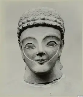 Limestone head and upper bust with curled hair and large almond-shaped eyes