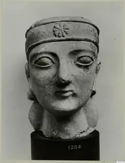 Limestone Neo-Cypriote head of a figure wearing a headband, shown on a dark cylindrical stand