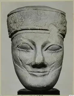 Limestone head with a carved band of rosette-like flowers around its top, seen from the front