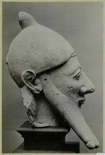 Limestone Proto-Cypriote statue head in profile, with a tall cap and a long projection from the chin.