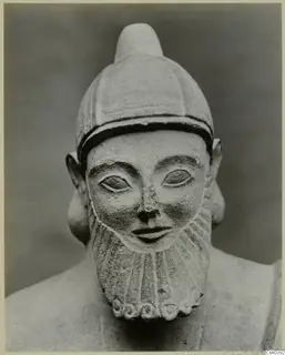 Limestone sculpture of a bearded head wearing a close-fitting cap, facing the camera
