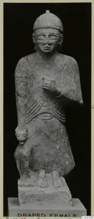 Limestone statue of a standing female figure with a small carved animal beside her, on a rectangular base