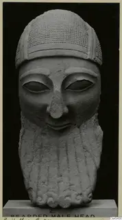 Limestone sculpture of a bearded male head on a plinth, seen from the front
