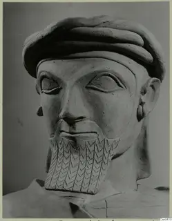 Terracotta bust of a bearded man in a thick rolled cap, with an incised pattern on the beard