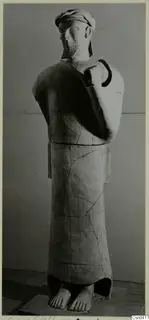 Terracotta statue of a bearded standing male figure with one arm bent up across the chest