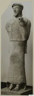 Terracotta statue of a standing bearded man, reconstructed from fragments and shown on a plinth