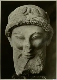 Limestone head of a bearded man with a curled headband, on a dark marble base