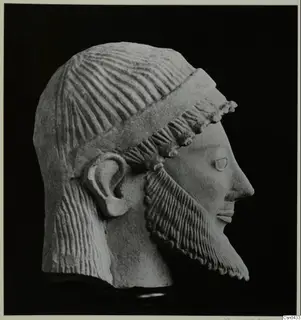 Limestone head of a bearded male sculpture in profile, facing right, with a band across the hair.