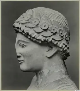 Limestone head of a figure in profile, wearing a carved wreath of flowers and leaves
