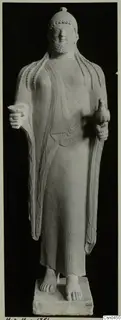 Limestone statue of a standing bearded figure holding a small bird.