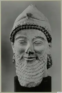 Limestone head of a bearded man in a tall cap, shown frontally on a black cylindrical stand