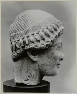 Limestone Cypro-Greek I head in profile on a dark stand, with incised hair and rows of locks.