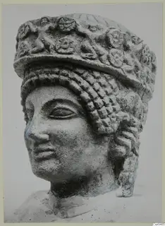 Limestone head from Arsos with a tall headdress decorated in relief and rows of curled hair