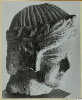 Limestone head of a figure from Mersinaki, shown in side view on a dark stand.