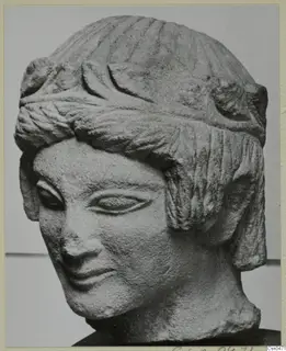 Limestone head sculpture from Mersinaki, three-quarter view, with hair bound by a broad band.