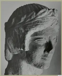 Limestone head from Mersinaki with carved, ridged hair and a broken nose.