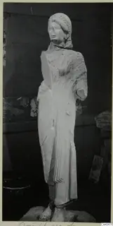 Limestone statue of a standing woman from Vouni, photographed against a dark wall.