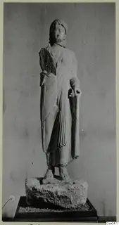 Limestone statue of a standing woman in a draped garment, set on a rough stone base