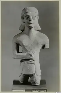 Limestone Neo-Cypriote statue of a human figure with one arm across the chest, on a dark base.