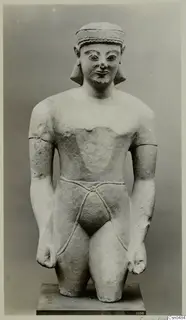 Limestone statue of a figure with a headband and cord belt, standing on a square plinth