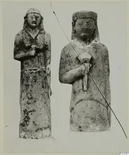 Two standing limestone statues of human figures, placed side by side.
