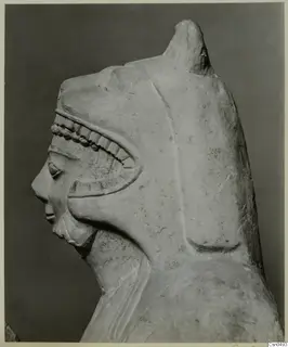 Limestone sculpture of a head in profile, with a tall headdress and a carved band of beads and notches across the brow