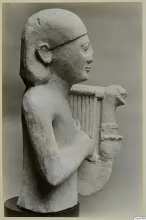 Limestone bust of a figure holding a lyre, shown in profile on a dark round base
