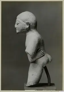 Limestone sculpture of a figure in profile, one hand resting on its waist, on a dark base