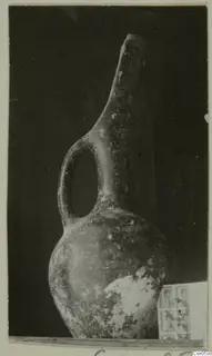 Jug with a tall narrow neck and a single loop handle, photographed against a dark background