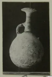 Pottery jug with a round body, loop handle and incised chevron pattern on a dark background