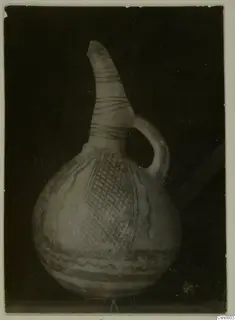 Pottery jug with a long narrow neck, single loop handle and painted bands and cross-hatching on the body