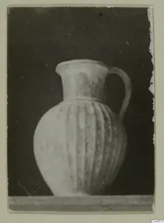 Jug with vertical ribbing on its body and a single loop handle, photographed against a dark background.