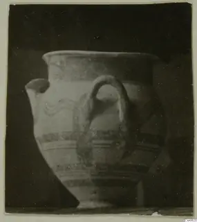 Pottery vessel with a loop handle, a spout and painted bands, shown against a dark background