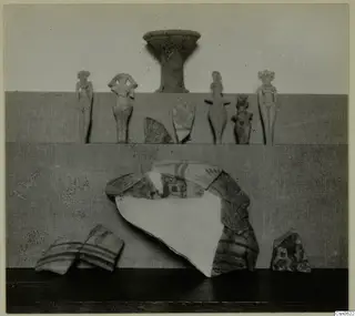 Five small figurines, a stemmed vessel and painted pottery sherds laid out on a board