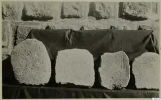 Four rough stone blocks set in a row on a dark cloth, stones from Kalopsidha
