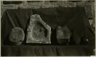 Five stone pieces from Alambra on a dark draped cloth, one with a circular hollow in its upper face
