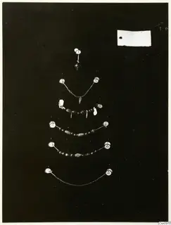 Several strands of beads and a pendant pinned on a dark board, each with a numbered label