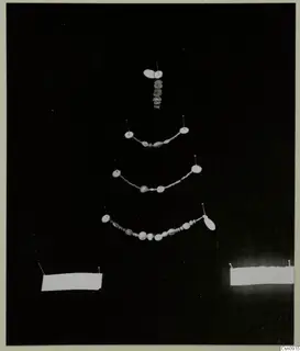 Several strings of beads and pendants pinned out on a black background for display.