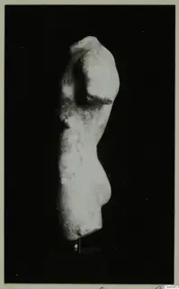 Headless stone statue torso in side view against a black background.