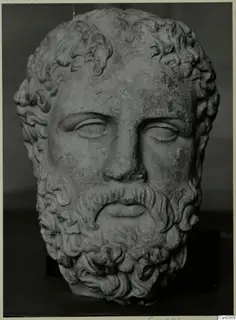 Bearded male head sculpture in stone, with wavy hair and beard and downcast eyes.