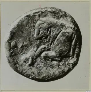 Find photograph of a round, flat object, probably a coin, with a raised design on one face, from Kountoura Trachonia