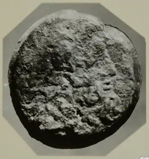 Round, heavily encrusted object from Kountoura Trachonia, shown on a grey octagonal mount