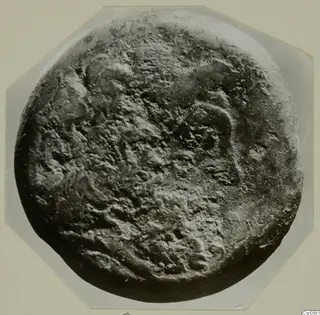 Heavily corroded round find from Kountoura Trachonia, photographed close up on a mount