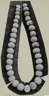 Necklace of pale, round beads laid in a long loop on a dark backing card
