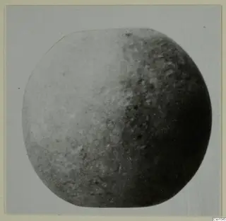 Rounded small find with a mottled surface, photographed on a card mount, from the Vrysi tou Barba tombs at Lapithos