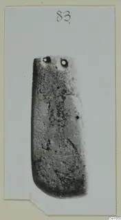 Rectangular stone object with two holes near its top end, photographed on a card mount.