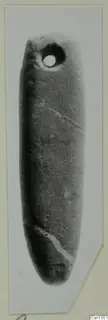 Elongated smooth stone object with a drilled hole near one end, photographed upright on a card mount