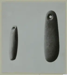 Two elongated, smooth pendants side by side, the larger with a drilled hole near its upper end.
