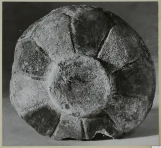 Bowl with radial segments and a raised central boss, photographed from above against a dark background